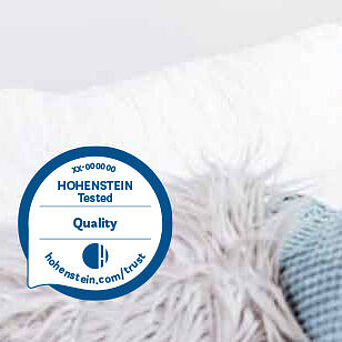 Home textiles Hohenstein Quality Label and a child peeking out from behind a couch