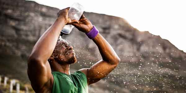 Runner in green shirt, pouring water over his head to cool down