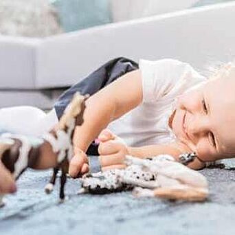 Toy Testing Child playing on carpeted floor with toys