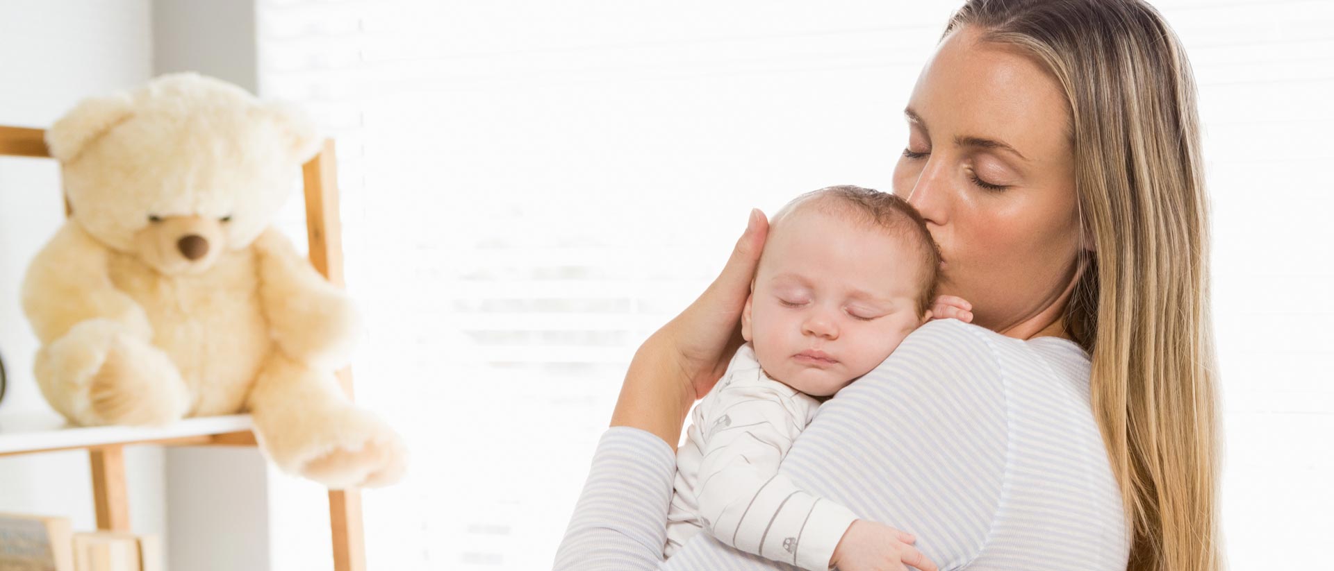 Contact-Safe Medical Product Considerations Mother holding baby near face in softly lit bedroom