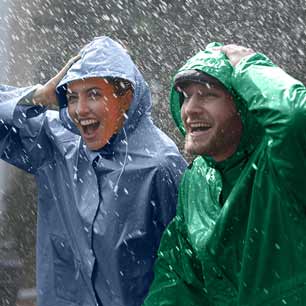 OEKO-TEX® and PFAS Woman in blue raincoat and man in green raincoat, shielding themselves from heavy rain