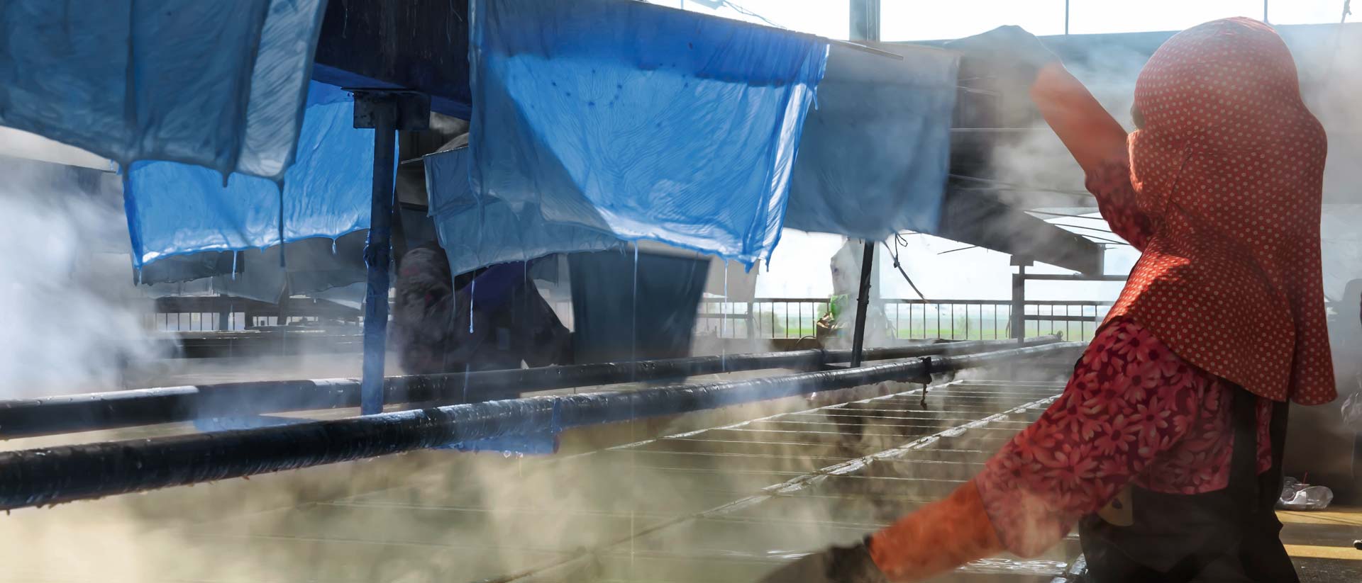 OEKO-TEX® STeP Certification for Sustainable Textile and Leather Manufacturing Textile worker hanging dyed cloth to dry in dyehouse